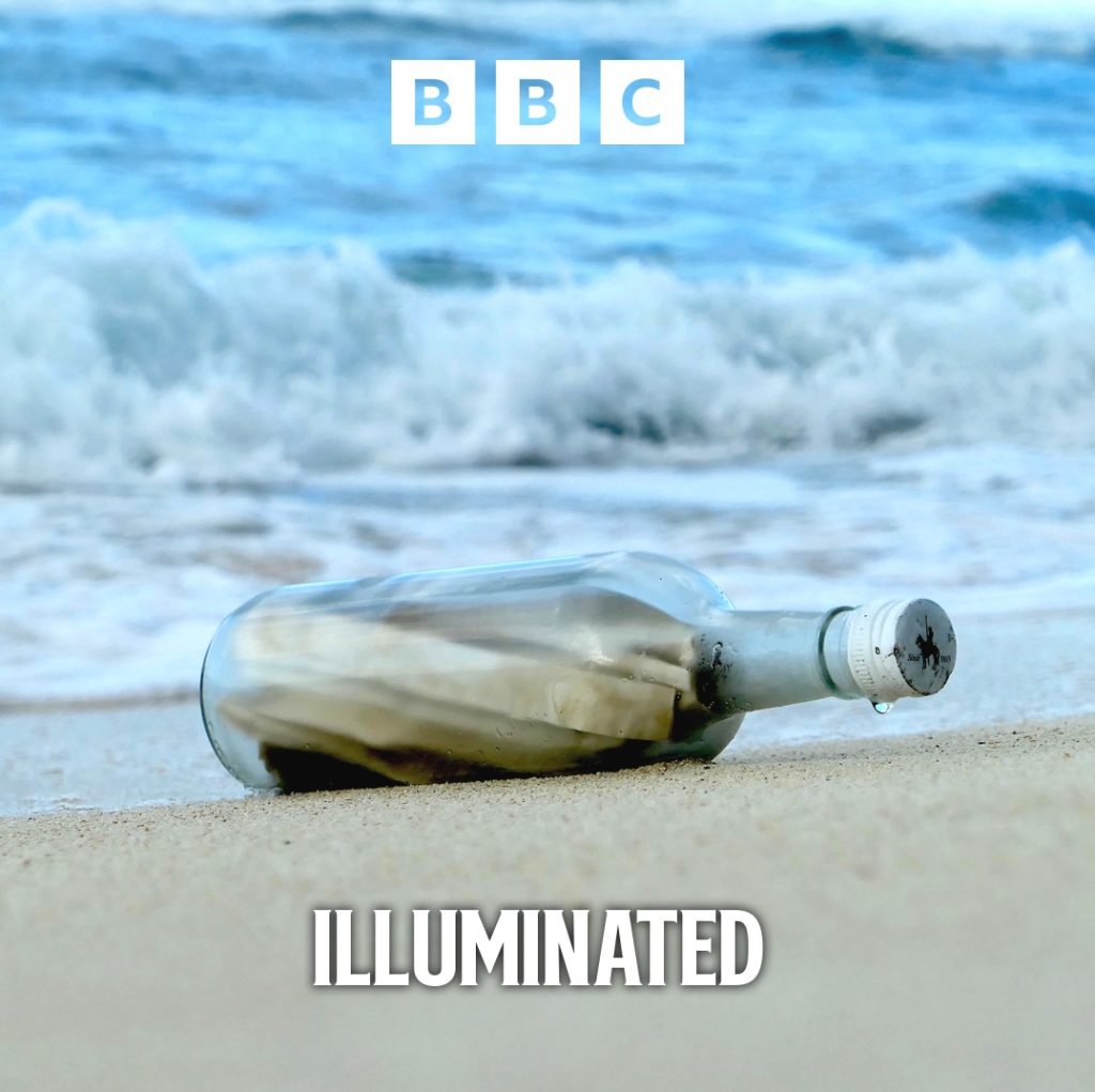 A bottle is washed up on a beach, we can see rolled up paper inside it
