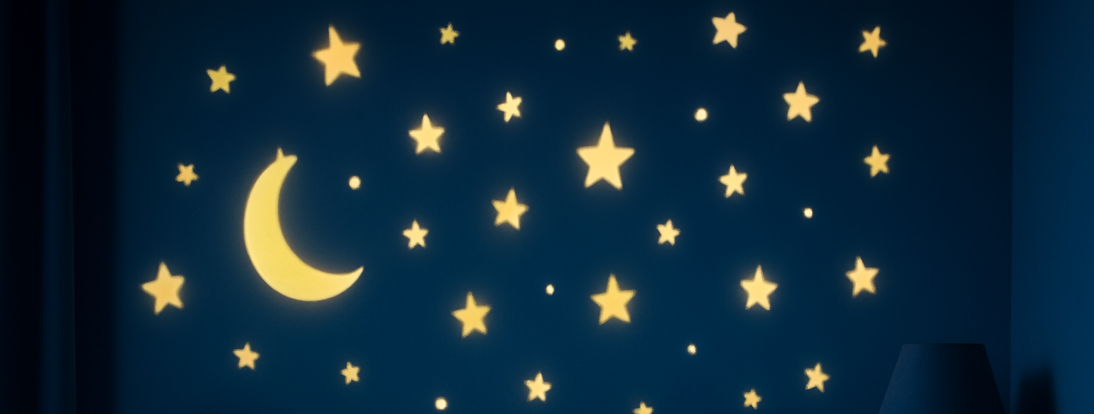 A child's bedroom, a teddy on the bed, stars and moon projected on the wall.